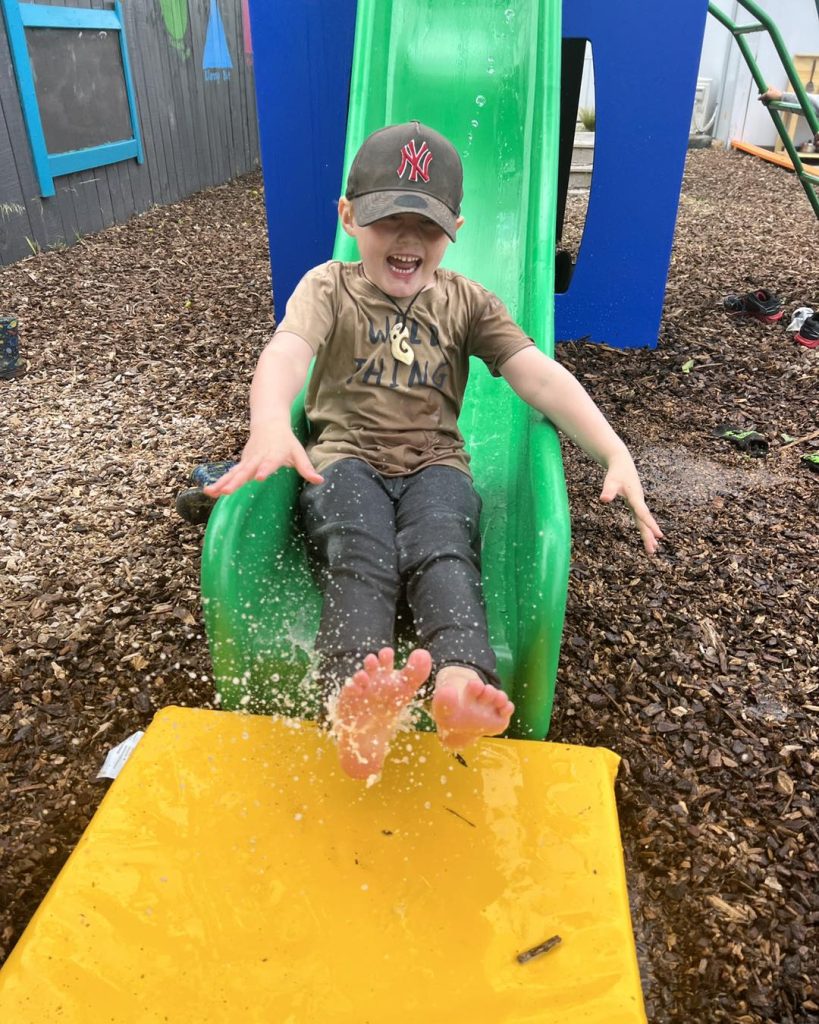 Child coming down slide through water