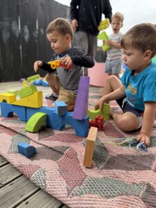 Children building colourful wooden blocks in an outdoor play area showcasing construction urge