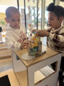 Two children putting toys together in a glass jar showcasing transformation urge
