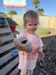 Child at Growing Wings Hamilton Centre holding a jar with dirt filled in it.
