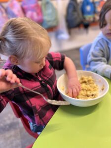 A child at Growing Wings Centre with a bowl of food during meal time and getting a feel for the daily routine.